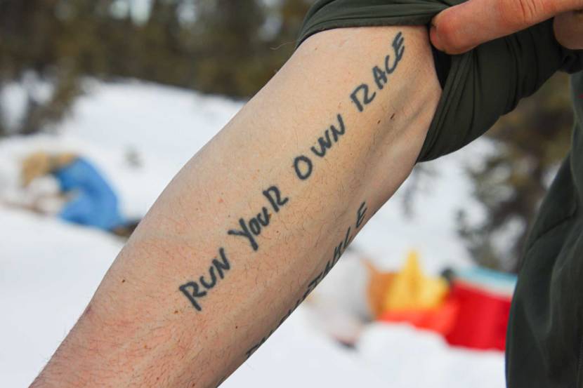 A sleeve rolled back to reveal a tattoo that says "run your own race"