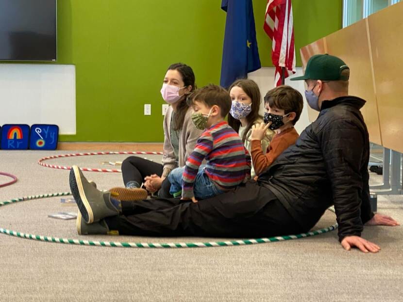 A family sits on the floor in a library during storytime