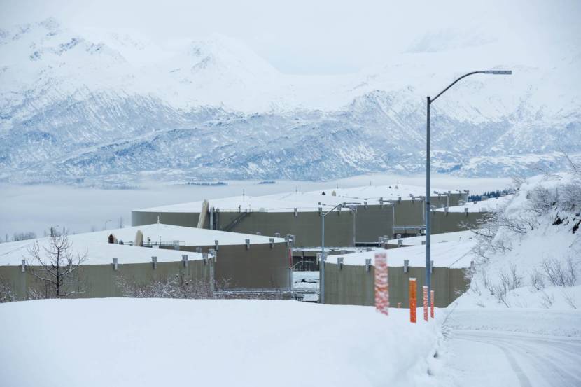 A group of large oil storage tanks with Valdez and mountains in the background