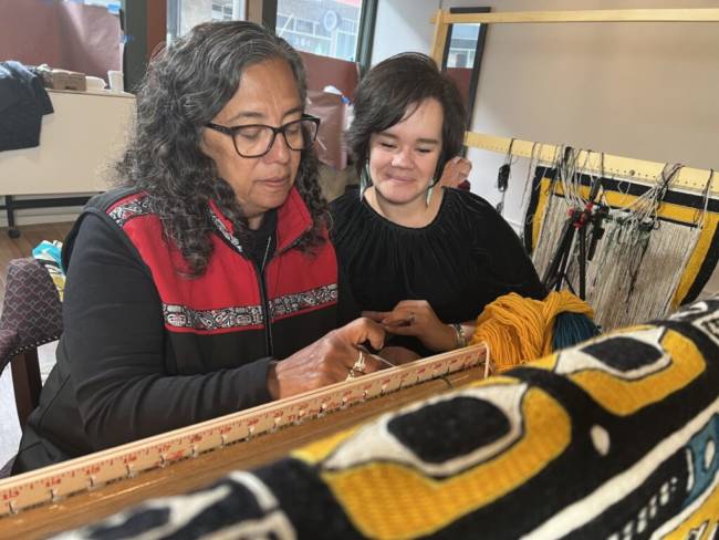 Two women weaving a blanket