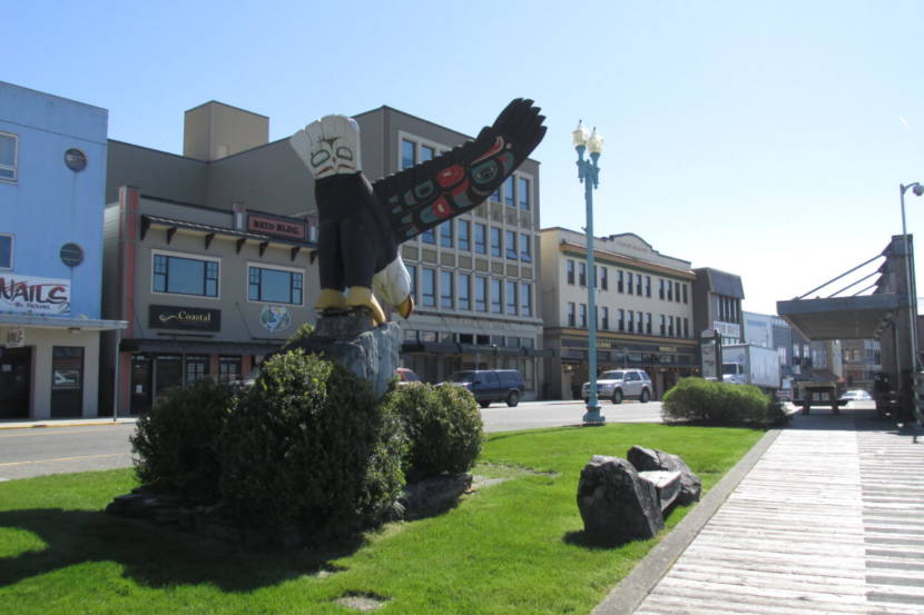 A huge wooden carving of an eagle perched on an actual rock on strip of grass in the middle of Ketchikan