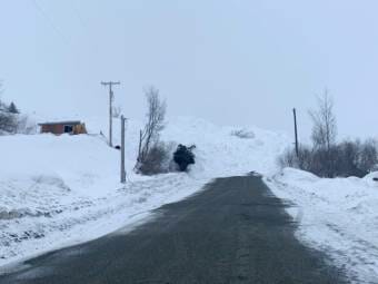 A massive pile of snow blocks a road