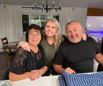A family photo of a daughter with her parents at a table