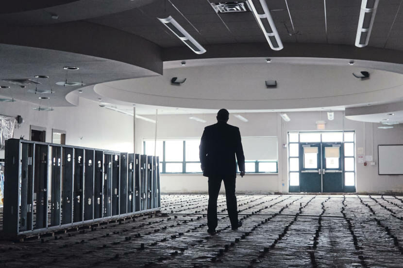 A man stands in a large room with a water-damaged floor