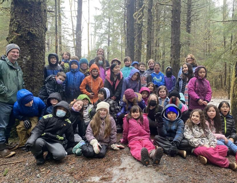 Juneau third grade teachers Geoffrey Wyatt and Ellen Canapary pose with their students in the forest on April 1, 2022. 