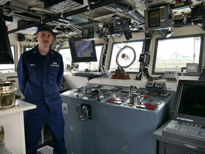 A man in uniform on the bridge of a Coast Guard cutter