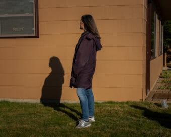 A woman seen in profile with her shadow cast against a house