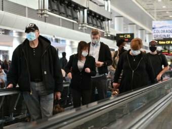 Masked travelers on an airport conveyer belt