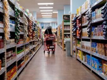 A shopper rolling a cart down a supermarket aisle