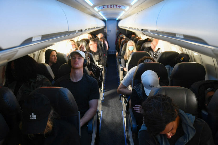 Passengers in a jet, some wearing masks and others not