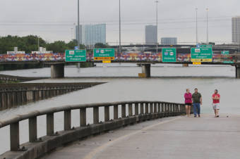 People standing on the on-ramp to a flooded interstate highway