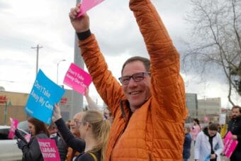A man in an orange down jacket holds up a sign at a rally for abortion rights
