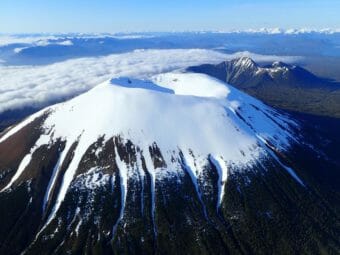 An aerial photo of the snow-covered crater at the summit of a volcano