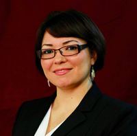 A professional headshot of a woman wearing glasses