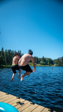 Two boys jumping into a lake at once