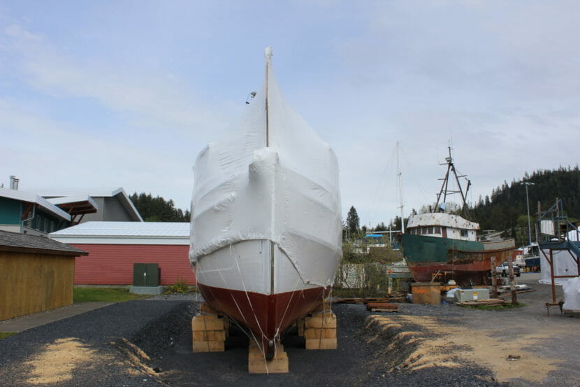 A wooden boat in a shipyard, wrapped up