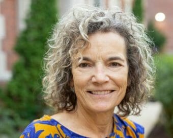 A headshot of a woman standing outside on a university campus