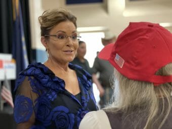 Sarah Palin speaks to a woman in a red baseball cap at a campaign event