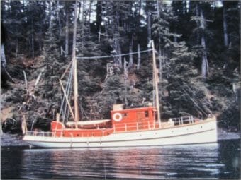 An old photo of a wooden patrol boat sailing along a forested coast
