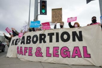 Demonstrators hold a large sign that reads "keep abortion safe and legal"