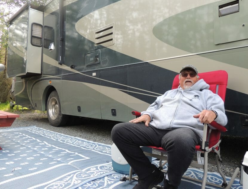 A man sitting on a camp chair beside an RV