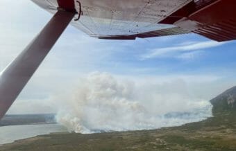 An aerial view of a large wildfire from the cockpit of a red airplane