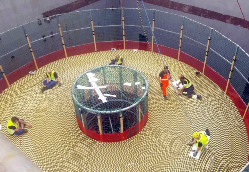 Workers on top of a giant spool of cable on a ship