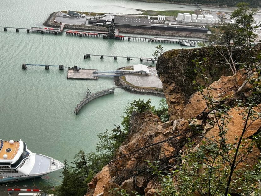 A mass of rocks on mountain slope with a cruise ship docked below.