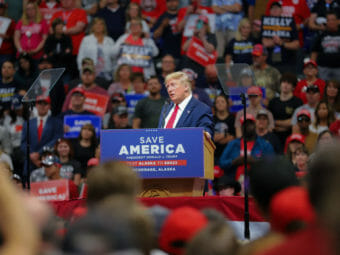 Donald Trump speaking at a rally in an auditorium