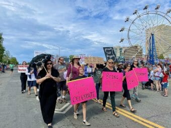 A group marching in a parade holding pink signs in support of access to abortion