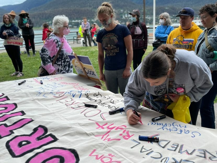 Demonstrators drawing on a large, white banner in support of abortion rights