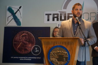 Alaska Health Commissioner Adam Crum stands behind a lectern