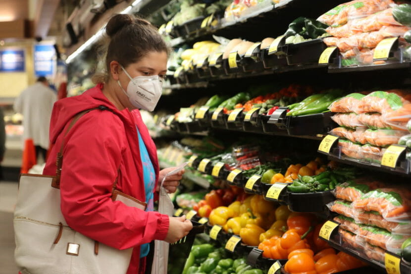 A woman shopping in the produce aisle of a grocery store