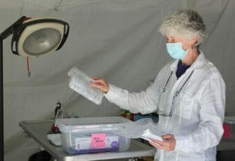 A woman in a lab coat going through a tote of supplies