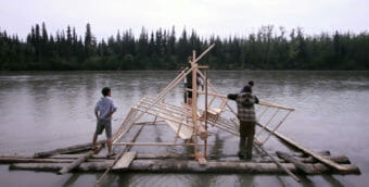 People building a fish wheel on a river