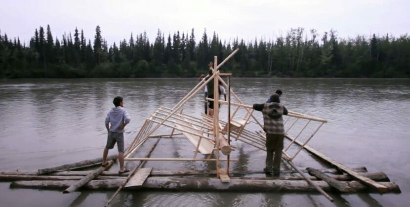 People building a fish wheel on a river