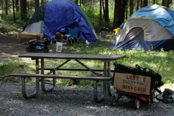 Tents at a campground and a sign that says "lost everything need cash"