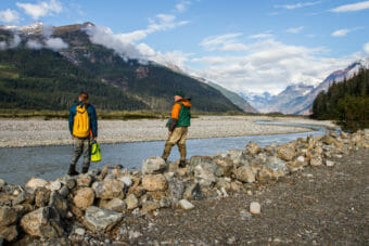 Two men stand by a stream in a remote river valley