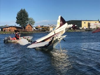 A badly damaged plane partially submerged, nose down, in a floatplane lagoon