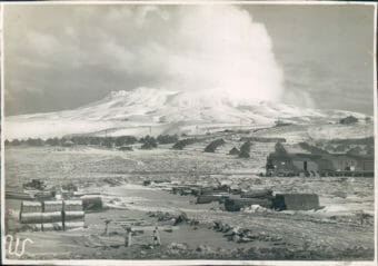 A black and white photo of Adak Island during WWII, with many tents set up and military equipment strewn about