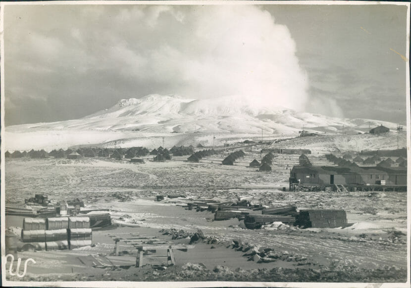 A black and white photo of Adak Island during WWII, with many tents set up and military equipment strewn about