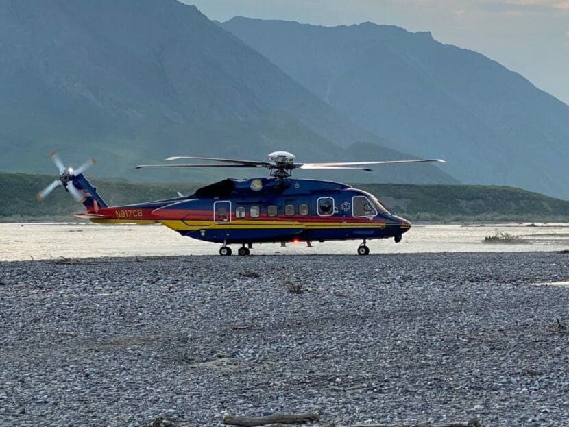 A large helicopter on a sandbar by a river
