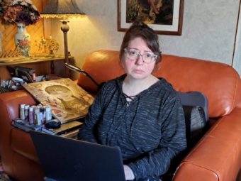 A woman sits in an armchair holding a laptop