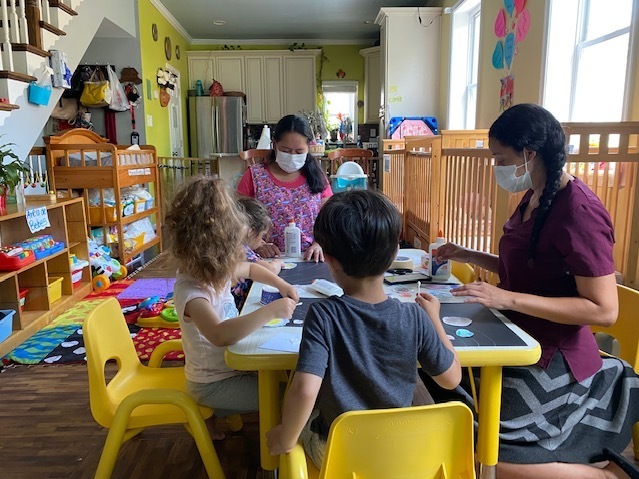 Children and adults around a table at a day care center