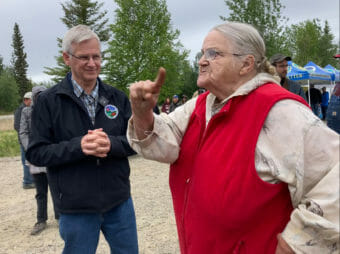 An older woman raises her finger while talking to a state official