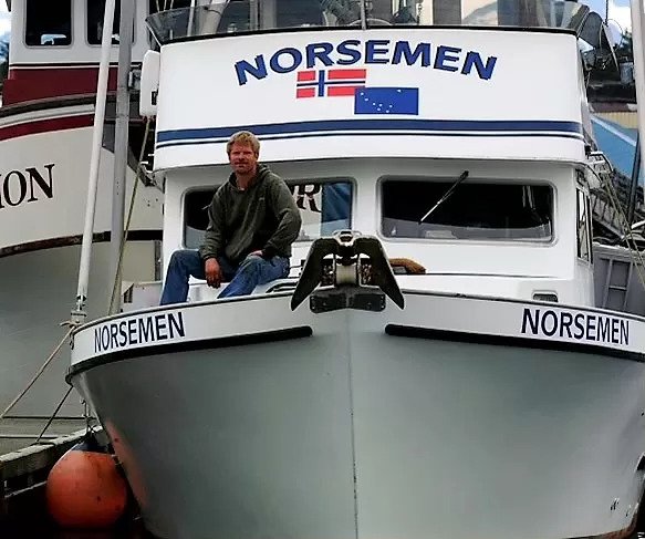 A man sitting on the bow of a boat called the Norseman