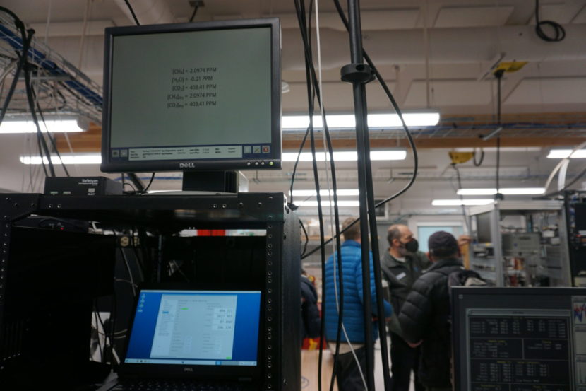 Computer monitors in a lab, with people standing in the background