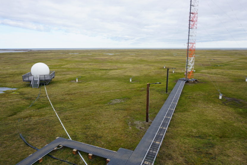 A white sphere and an open tower on the tundra, accessed by walkways