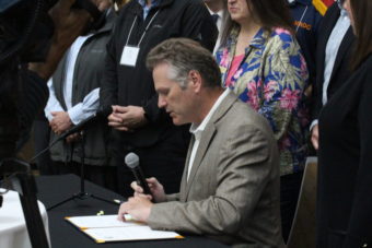 Gov. Dunleavy sitting at a table and signing a bill