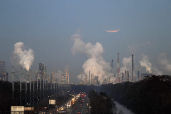 Emissions rising from a heavy industrial area with a highway running through it